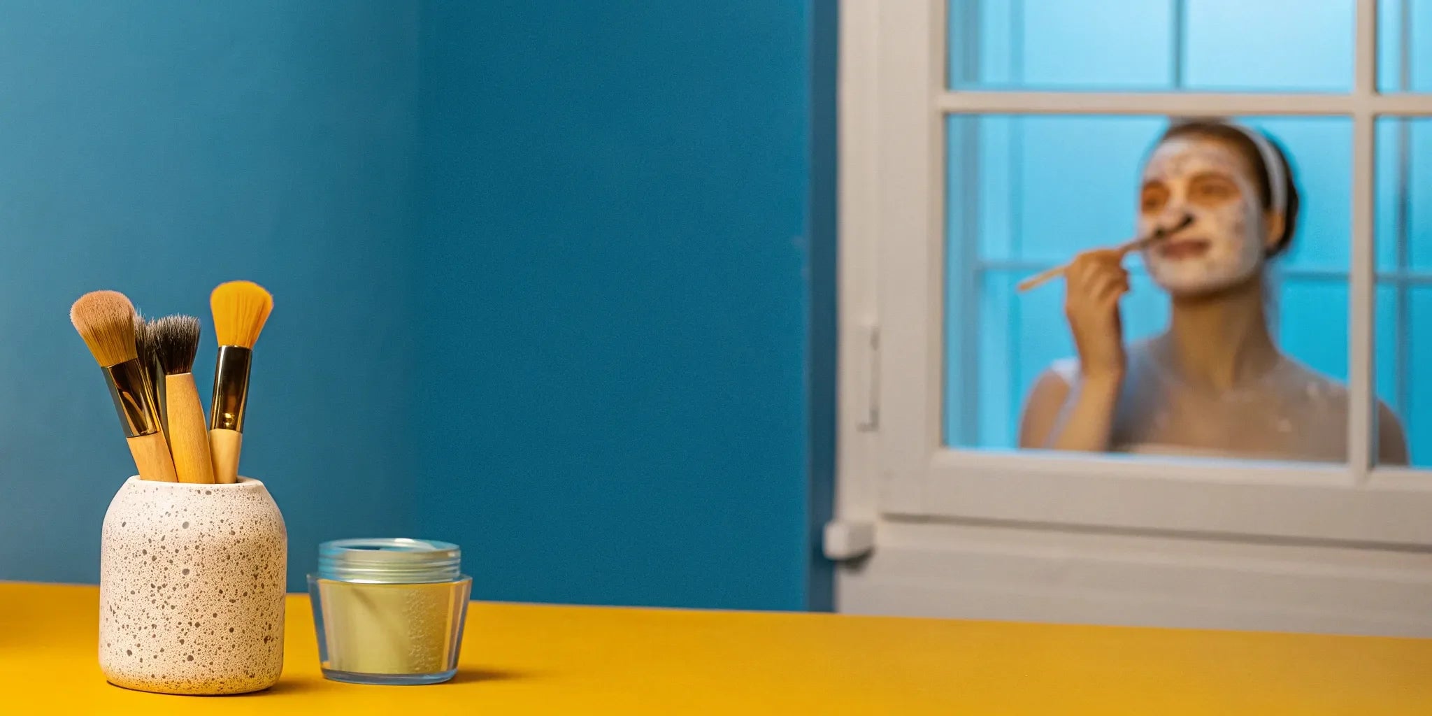 Woman applying a face mask as part of an at-home facial for dull skin.