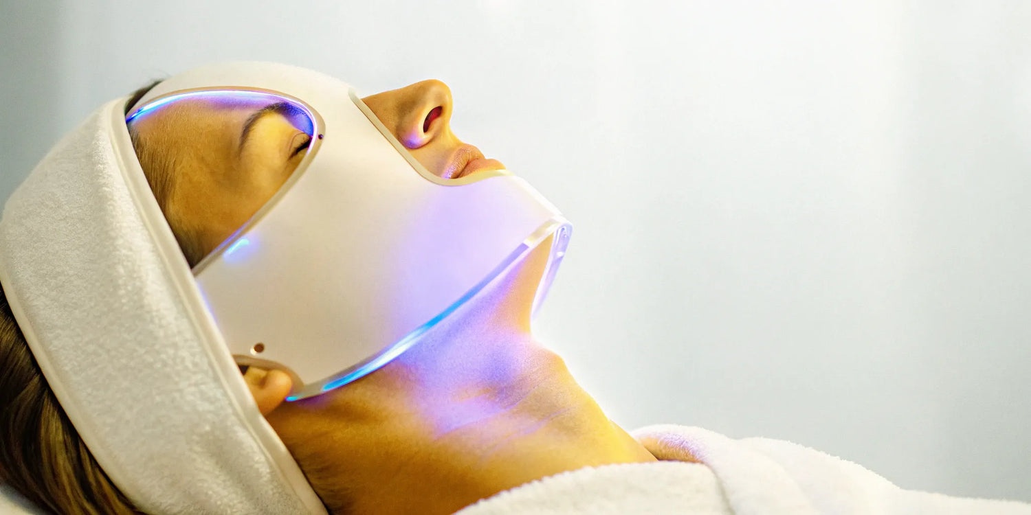 A person using an LED face and neck light therapy mask.