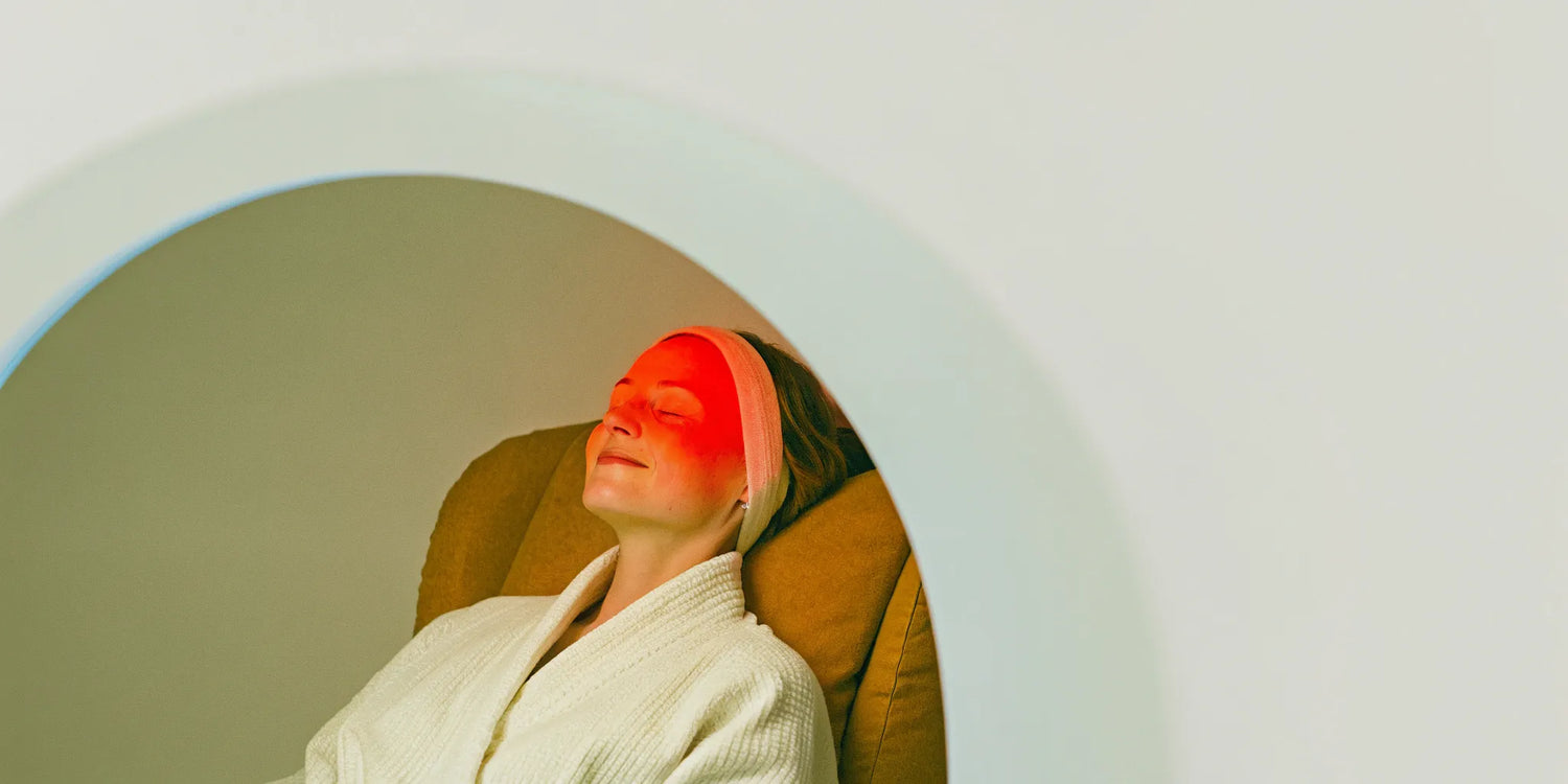 Woman using red light therapy on her forehead to reduce wrinkles.