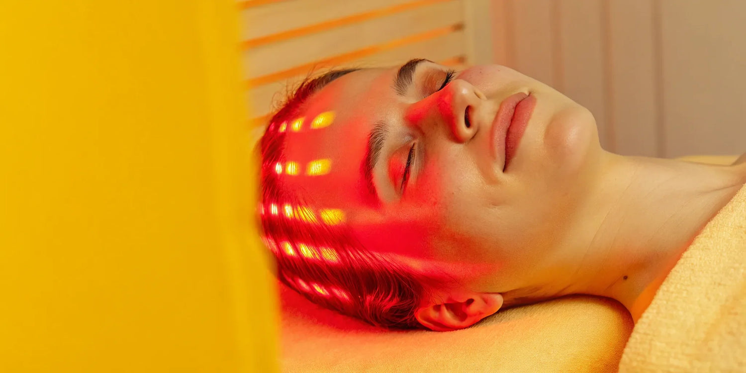 A woman receives red light therapy on her face, a treatment with pros and cons.