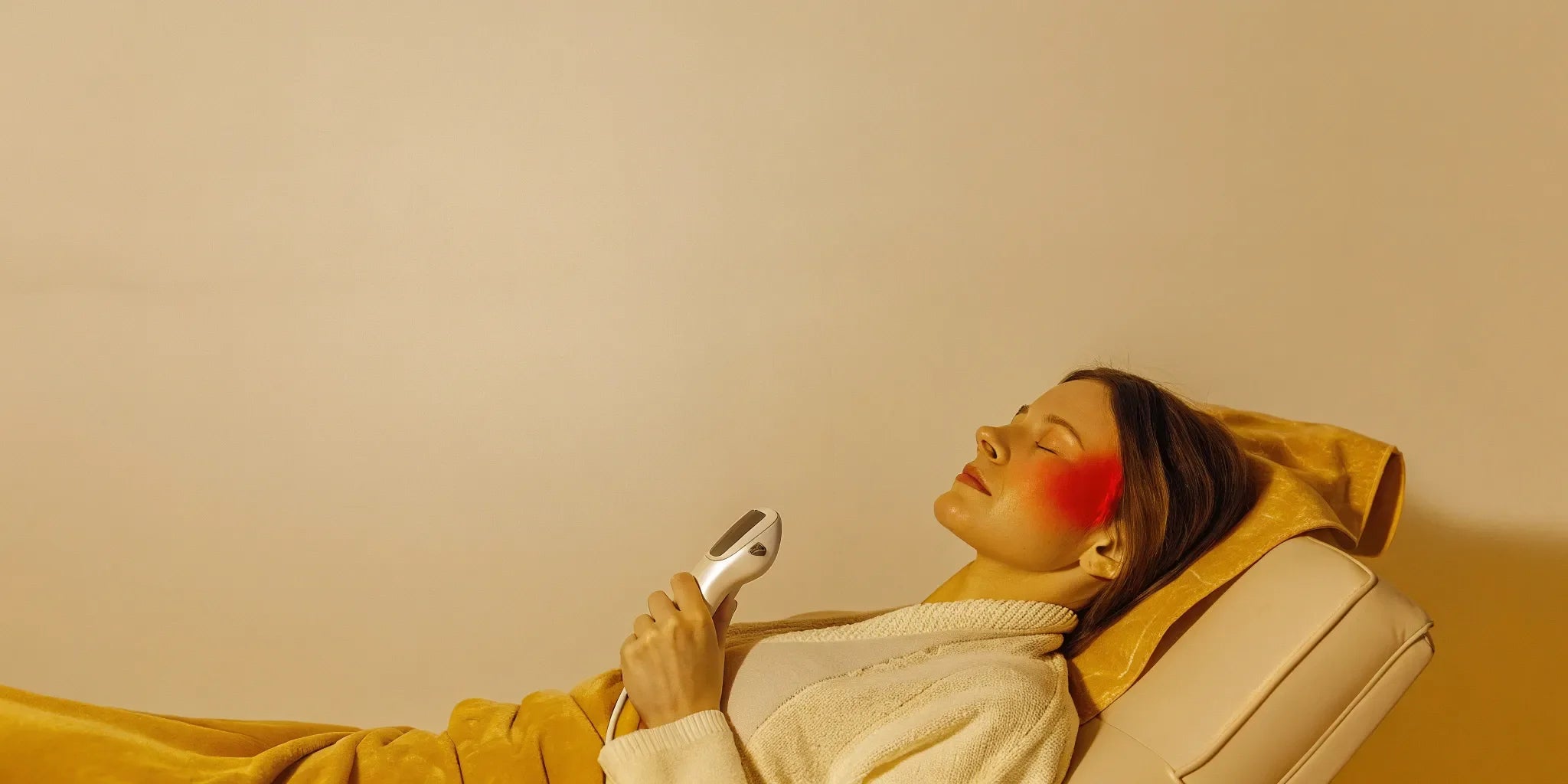 Woman using strongest red light therapy device at home for facial treatment.