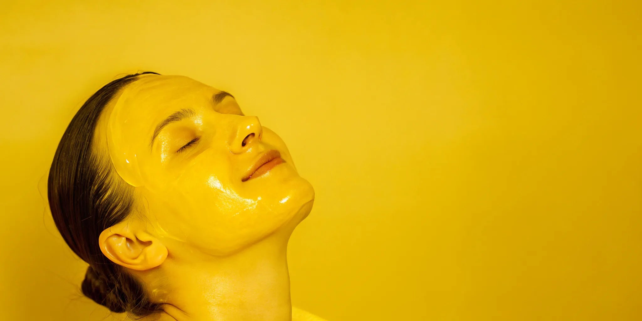 Woman using red light therapy with a facial mask to stimulate collagen production.