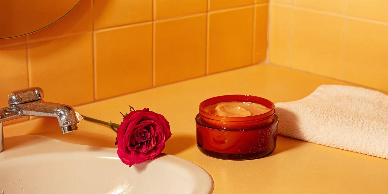 A collagen boosting renewal mask in an amber jar, displayed on a bathroom counter.