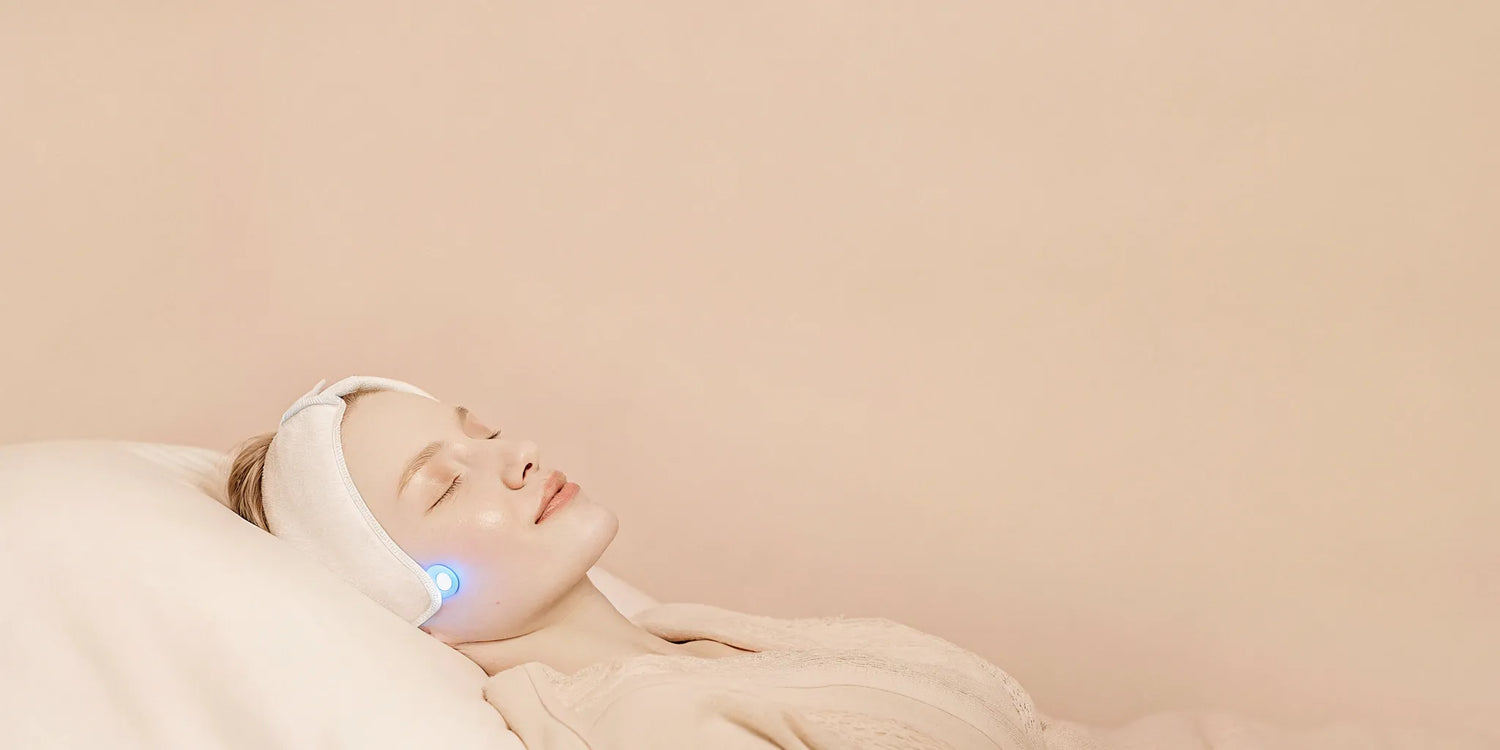 Woman using a blue LED light therapy mask for acne treatment.