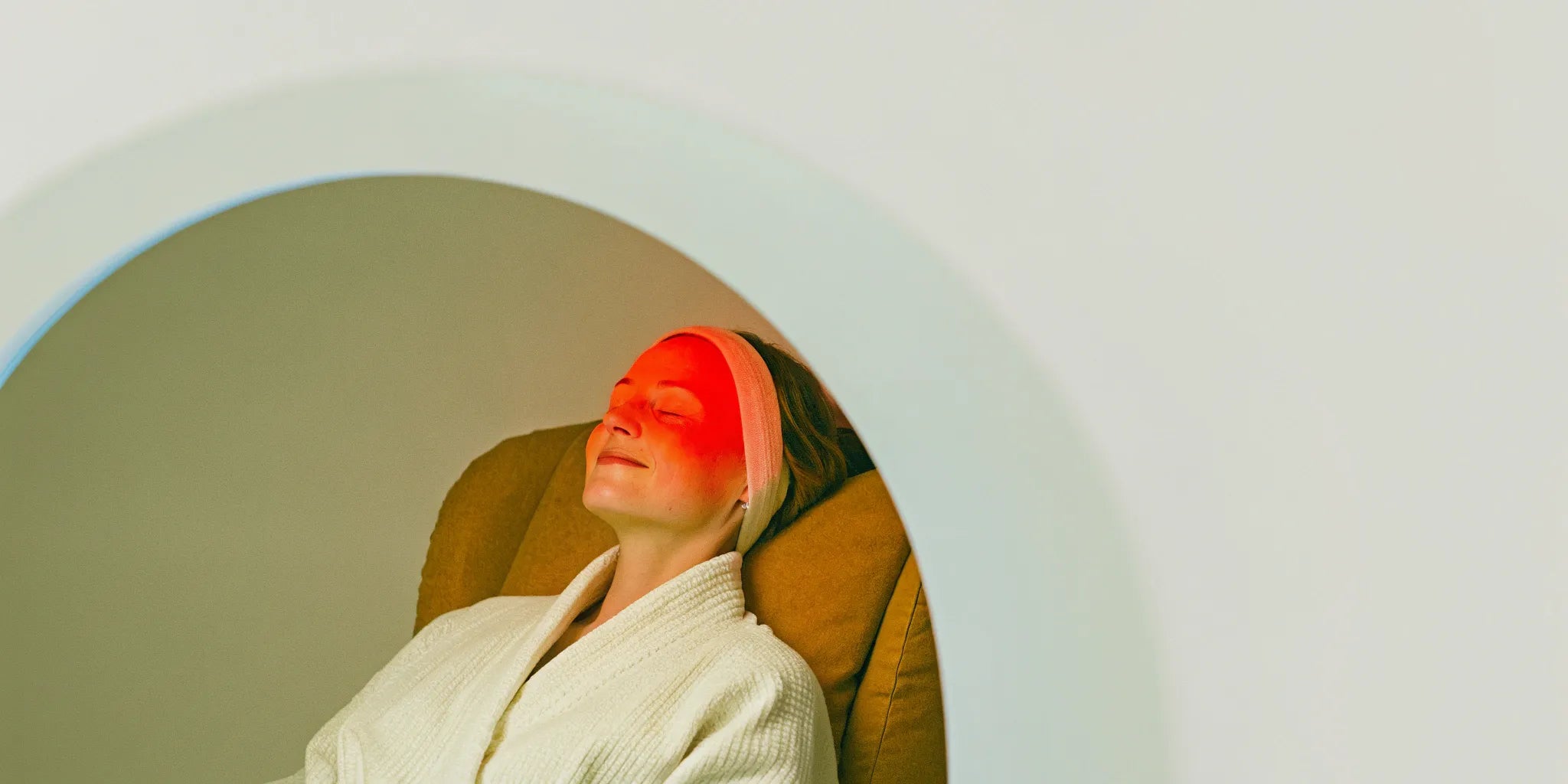 Woman using red light therapy on her forehead to reduce wrinkles.